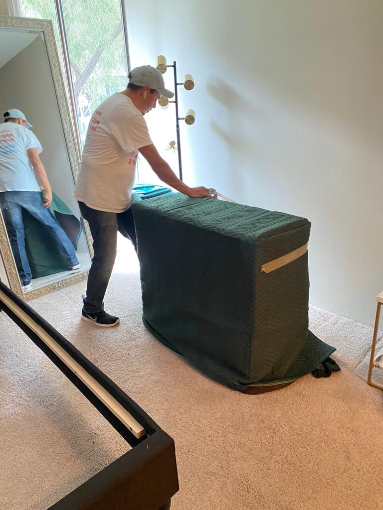 Mover wrapping a protective cover over furniture inside a home by the entrance.